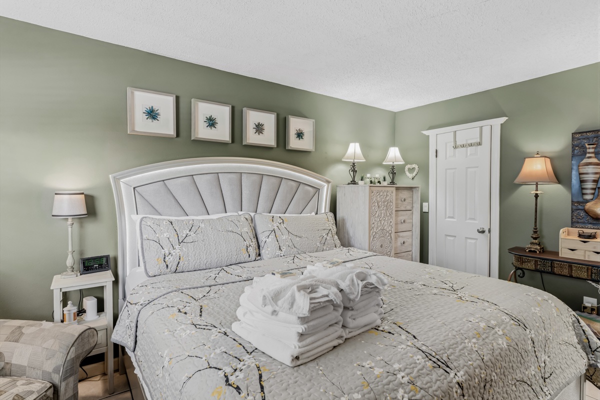 Sink into your plush bed surrounded by calming sage-green walls and coastal décor. Fresh linens await, with bedside lamps and a wardrobe ready for your stay.