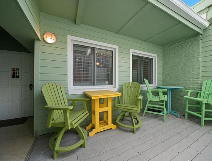 Your private covered deck invites you to relax in vibrant green swivel chairs around a sunny yellow table, perfect for morning coffee or evening conversations.