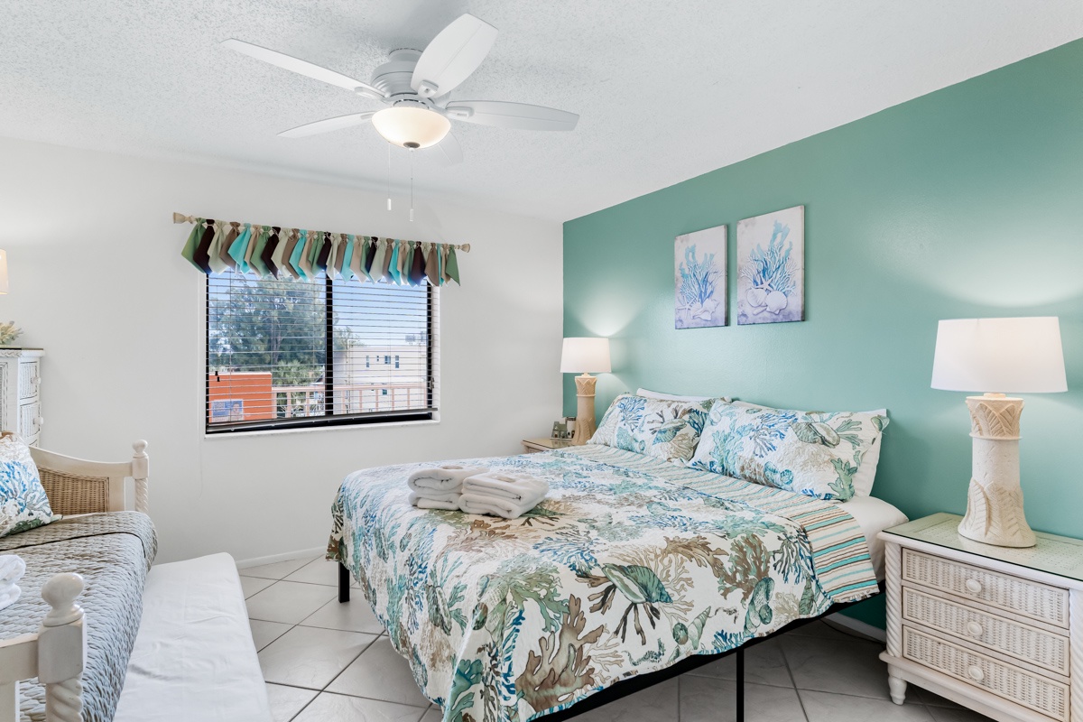 Drift off to sleep in this cheerful bedroom featuring coastal decor, soft tropical bedding, and a gentle ceiling fan to keep you cool.