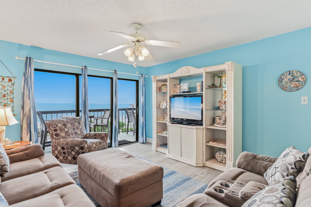 Step into your coastal retreat where soothing blue hues and comfortable furnishings create the perfect backdrop for your beachside escape, with stunning ocean views just beyond your private balcony.