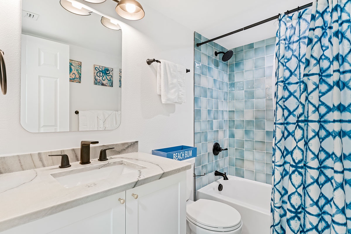 Your bright coastal bathroom features stunning blue mosaic tiles, modern fixtures, and beach-themed touches that create a refreshing spa-like retreat.