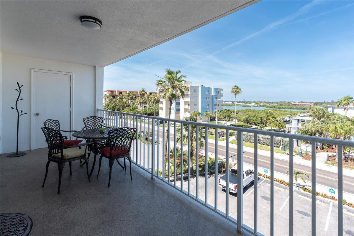 A spacious covered balcony with outdoor dining overlooking palm trees, waterfront views, and the tropical neighborhood—perfect for morning coffee or evening relaxation.