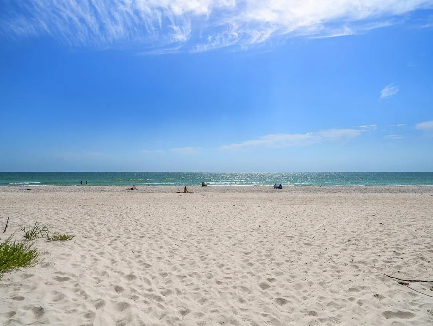 Pristine sandy beach with clear blue skies and gentle waves, perfect for relaxing days by the ocean.
