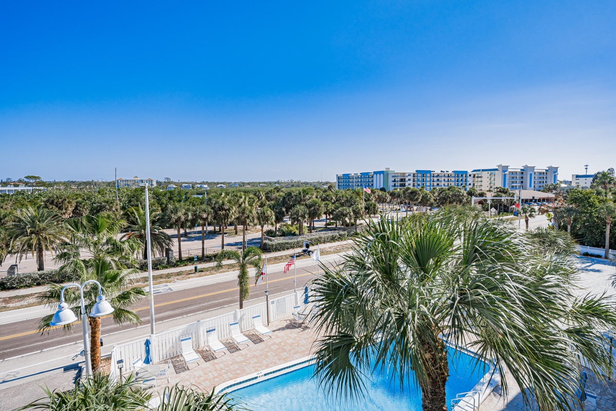 Elevated view showcasing the surrounding area with tropical palms, nearby accommodations, and local infrastructure creating a vibrant coastal destination.