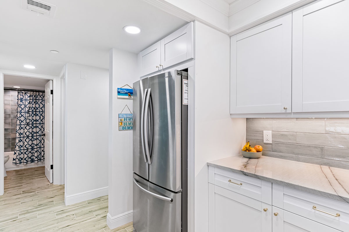 Your bright white kitchen features sleek cabinets, marble counters, and modern appliances for effortless vacation cooking.