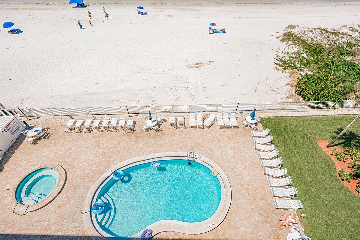 Beachfront property featuring swimming pool with direct beach access and poolside loungers.