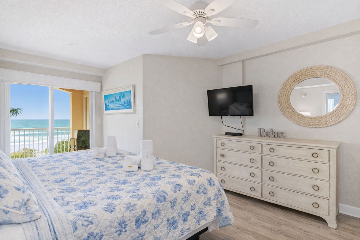 Your peaceful Primary bedroom offers stunning ocean views through the balcony doors, with soft coastal decor and modern amenities for ultimate relaxation.