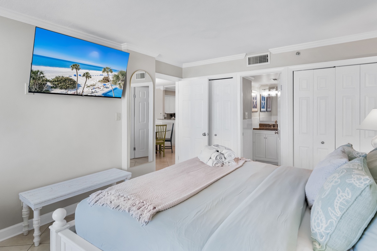 Unwind in your bright, coastal bedroom with crisp white linens, tropical TV views, and refreshing air conditioning for perfect sleep comfort.