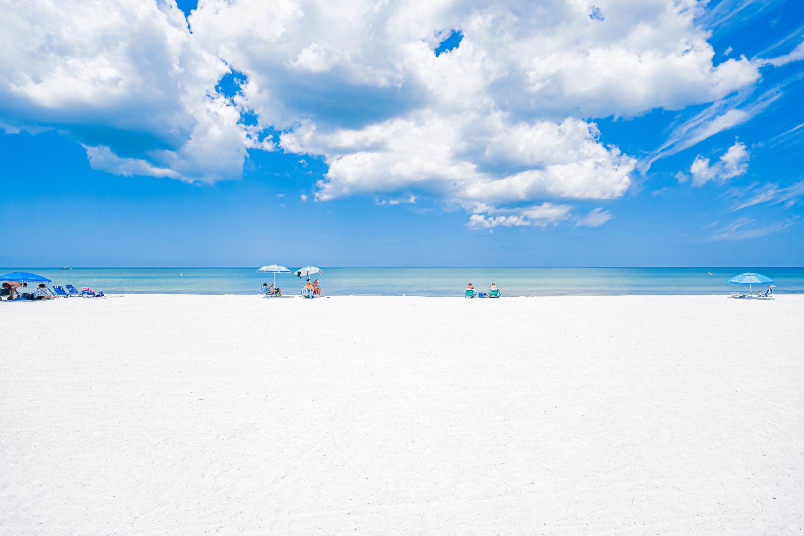 White sand beach with calm blue waters under dramatic clouds—a nearby coastal setting perfect for day trips and relaxation.