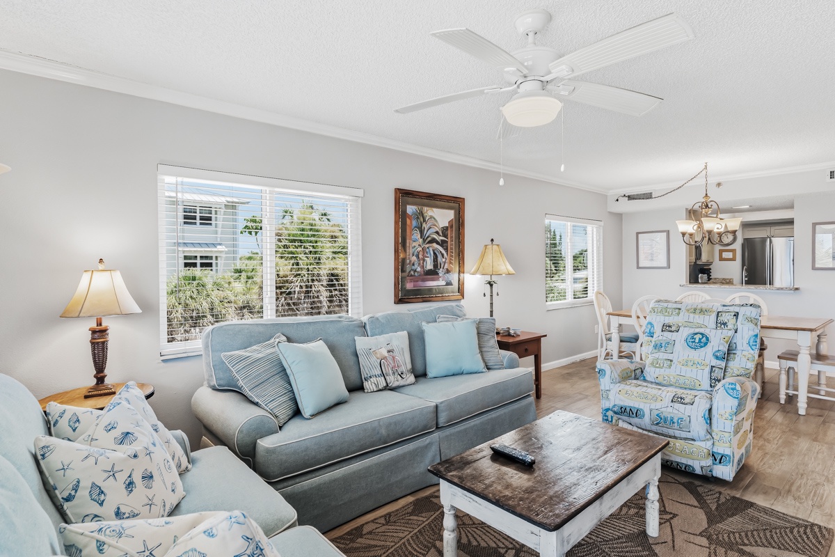 Unwind in your bright, coastal-inspired living room, where soft blues and beach-themed accents invite you to relax. Ceiling fan keeps you cool, and natural light fills the open space connecting you to the dining area.