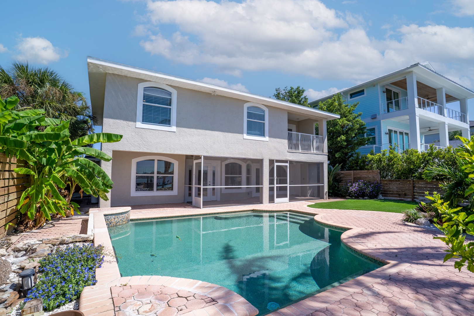 Beachside vacation home with private pool surrounded by tropical landscaping and neighboring coastal properties.