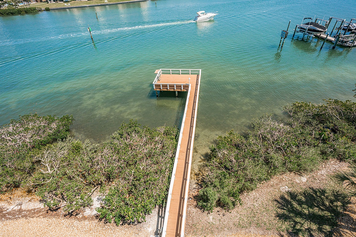 Private waterfront property with direct access pier extending into pristine turquoise waters, surrounded by natural coastal vegetation and established boat docks.