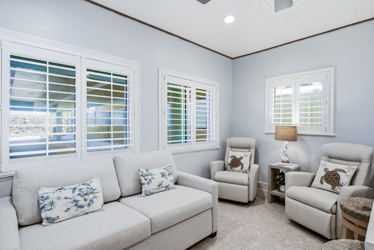 Sink into plush seating surrounded by soft coastal hues and natural light with shuttered windows in your peaceful retreat.