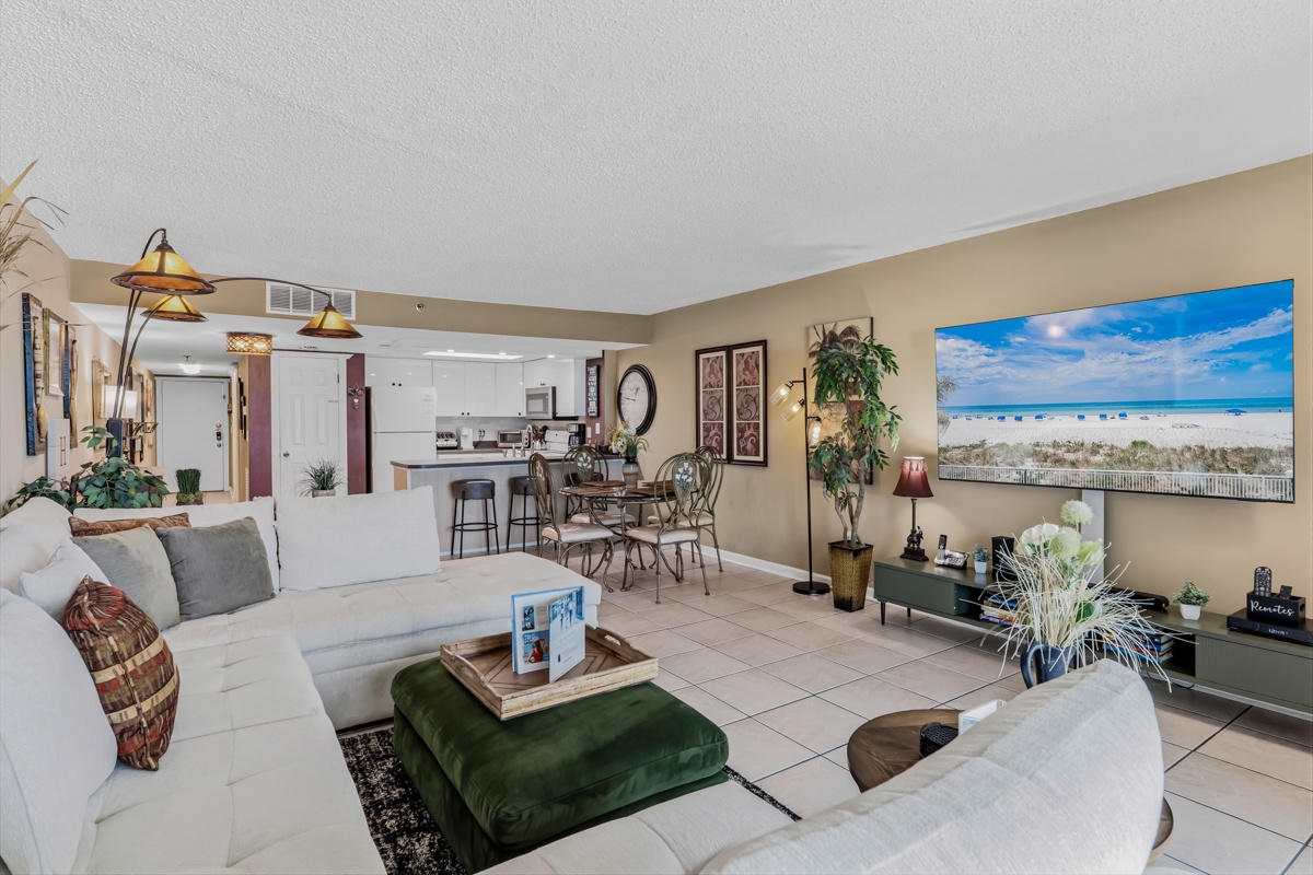 Relax in your spacious, light-filled living area with comfortable seating, ocean-inspired décor, and open-plan kitchen—perfect for unwinding after beach adventures.