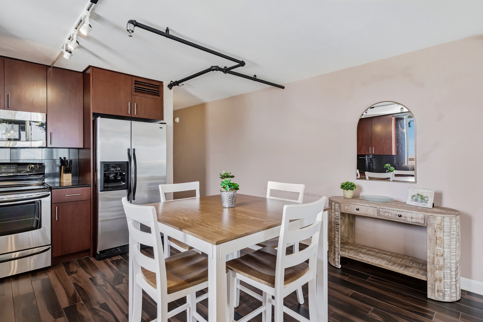 Your dining space blends warm wood tones with modern touches, inviting you to share meals around the welcoming table while sleek appliances stand ready nearby.