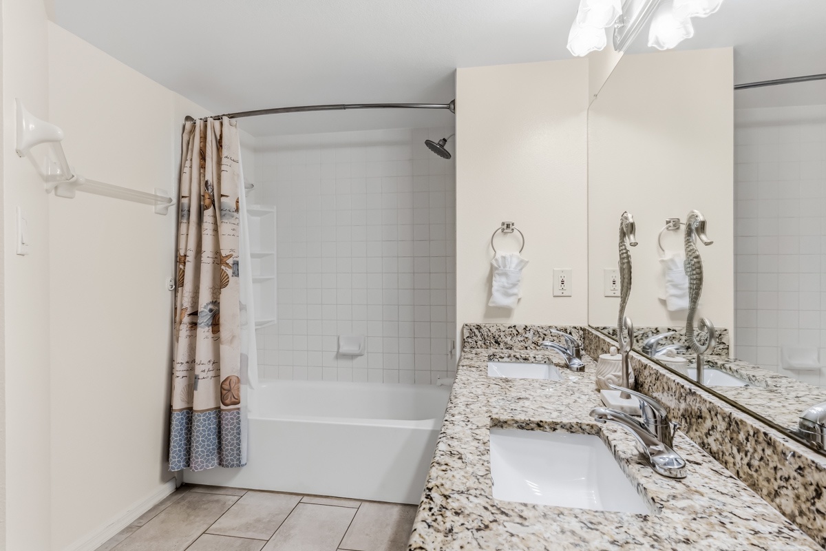 Freshen up in your private bathroom featuring granite countertops, rainfall shower, and coastal charm with natural light.