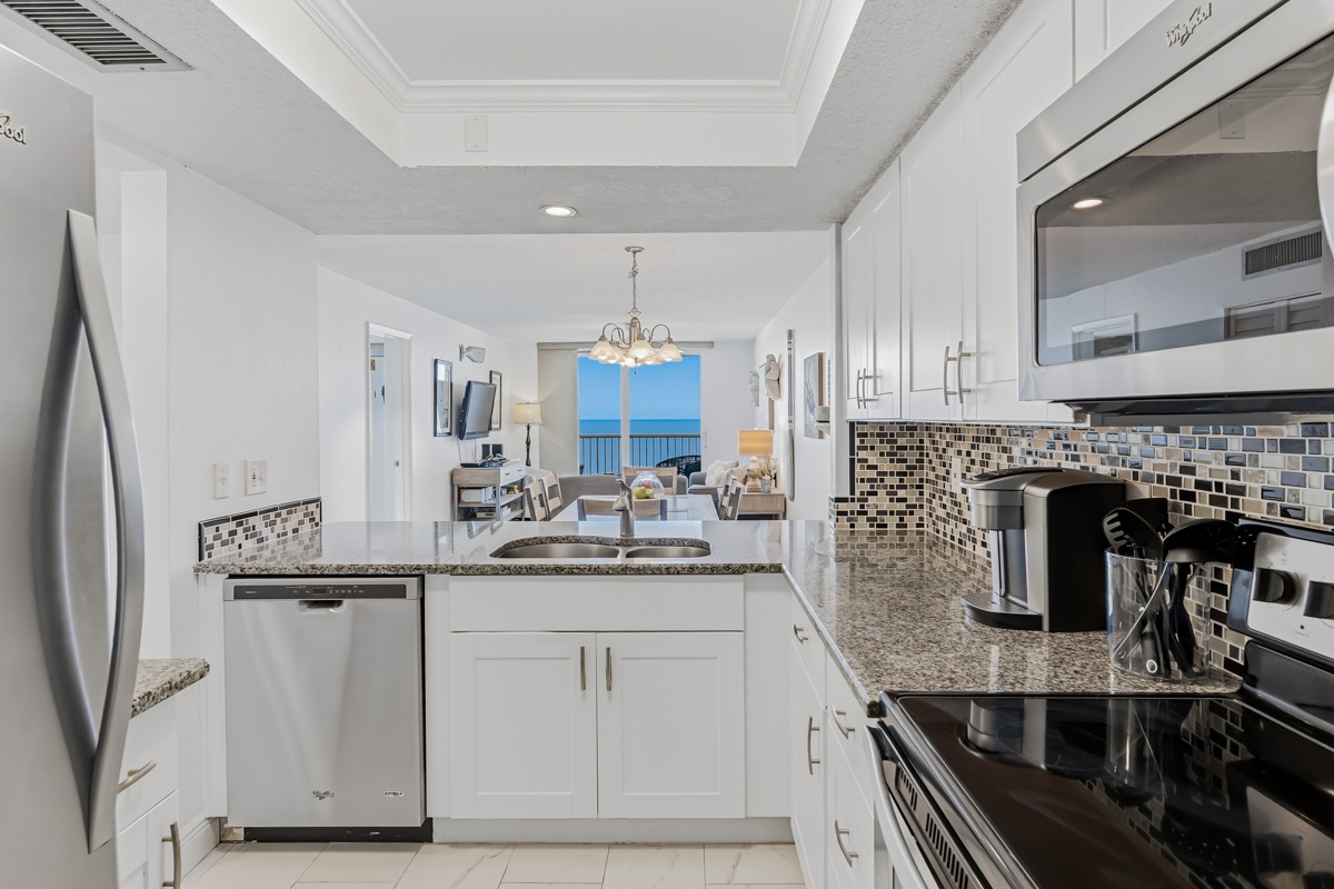 Your modern kitchen features granite counters, stainless appliances, and stunning ocean views through the dining area windows.