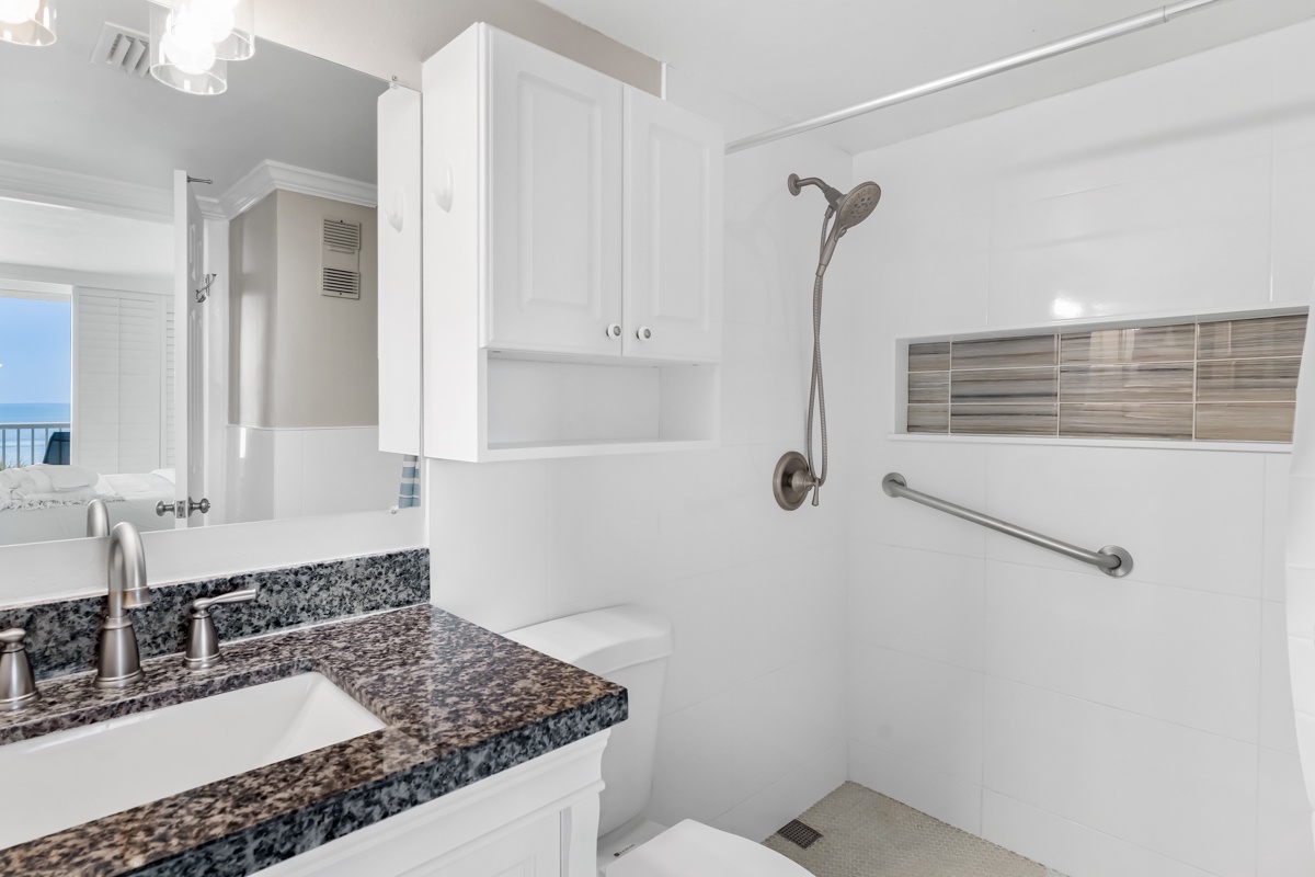 Step into your bright, accessible bathroom featuring granite countertops, modern fixtures, and safety grab bars for comfort.