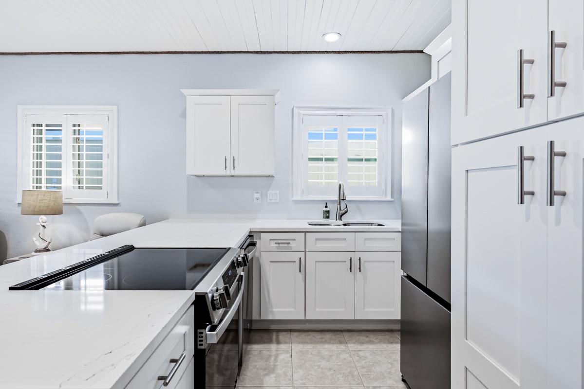 Your bright, fully-equipped kitchen awaits with pristine white cabinetry, sleek countertops, and stainless steel appliances for all your culinary adventures.