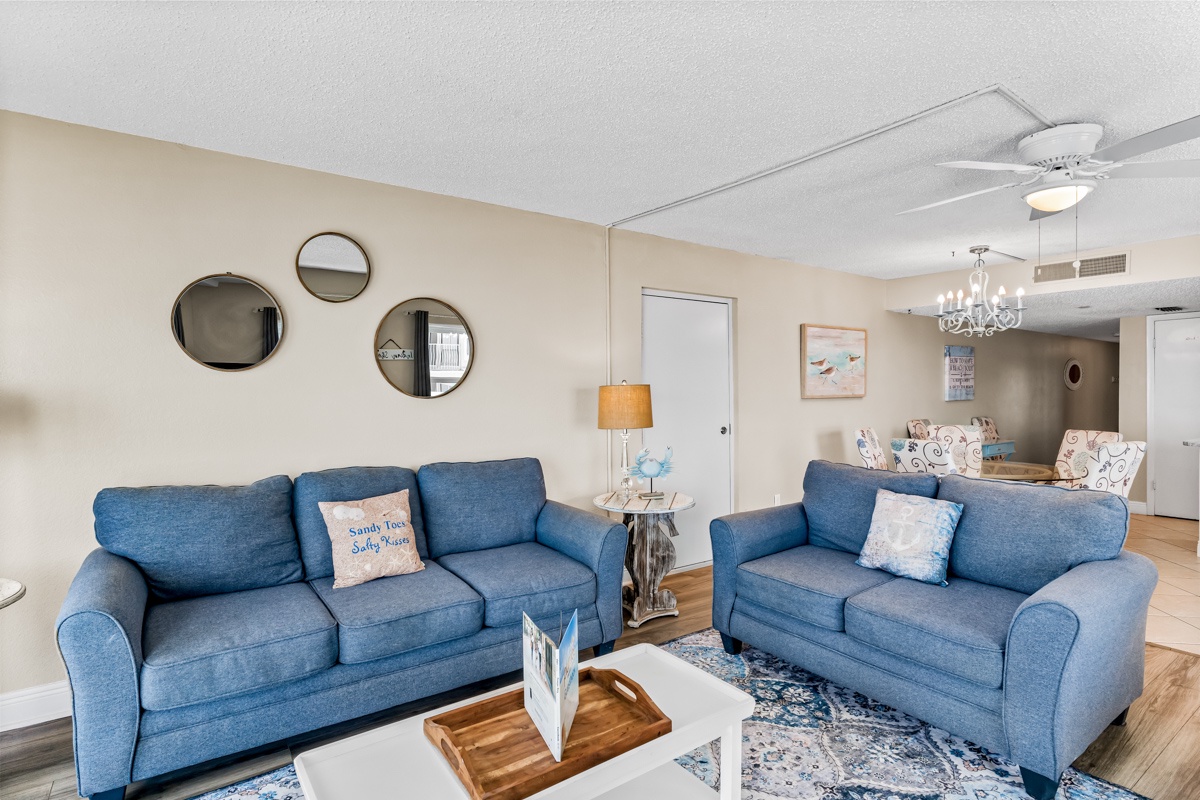 Sink into plush blue sofas where coastal charm meets comfort, with stylish mirrors reflecting natural light throughout your spacious retreat.