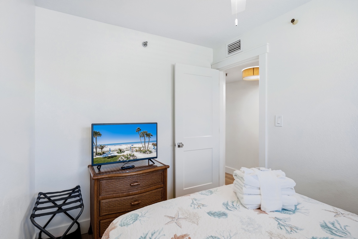Relax in your cozy bedroom with ocean-themed bedding, flat-screen TV, and thoughtful touches like fresh towels and luggage rack for your convenience.
