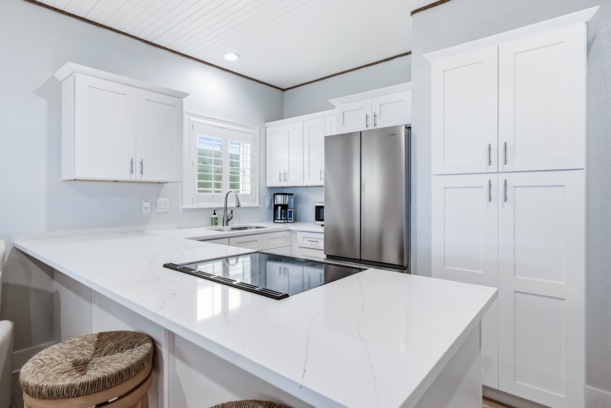 Your pristine white kitchen gleams with marble countertops and modern appliances, perfect for crafting memorable meals during your stay.