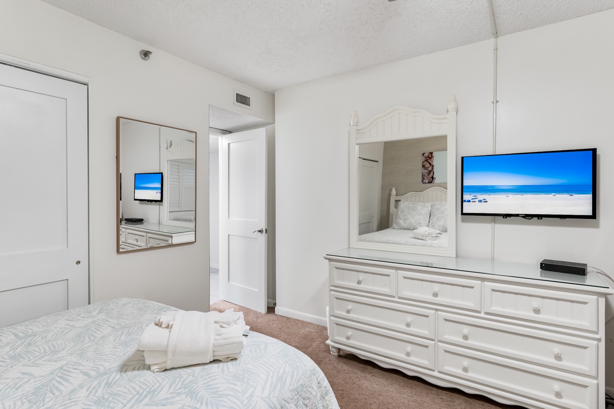 You'll love the crisp, coastal style of your bedroom, with its fresh white furnishings and calming palette. Fluffy towels are ready for your beach days, and the large mirror adds a touch of elegance to the space.