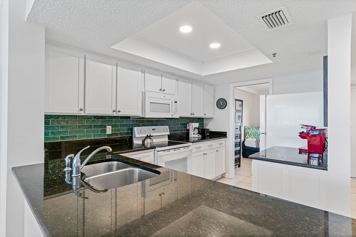 Your fully equipped kitchen features granite countertops, modern appliances, and a charming green tile backsplash—perfect for preparing meals during your stay.