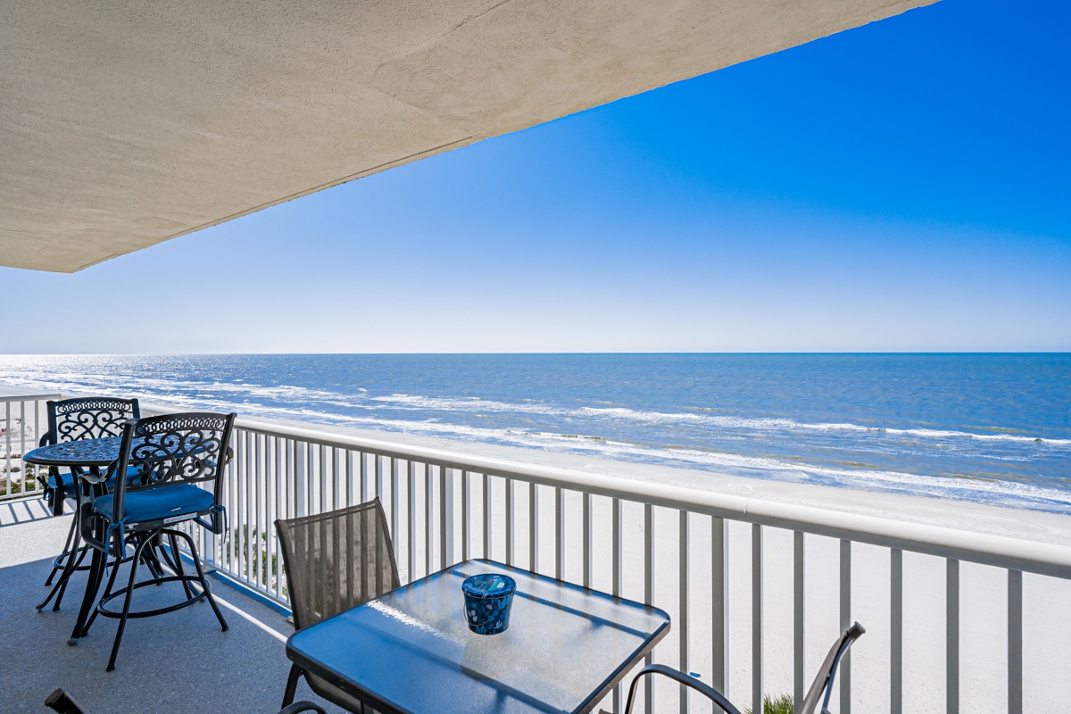 Your private oceanfront balcony awaits with comfortable dining furniture and endless beach views stretching to the horizon.