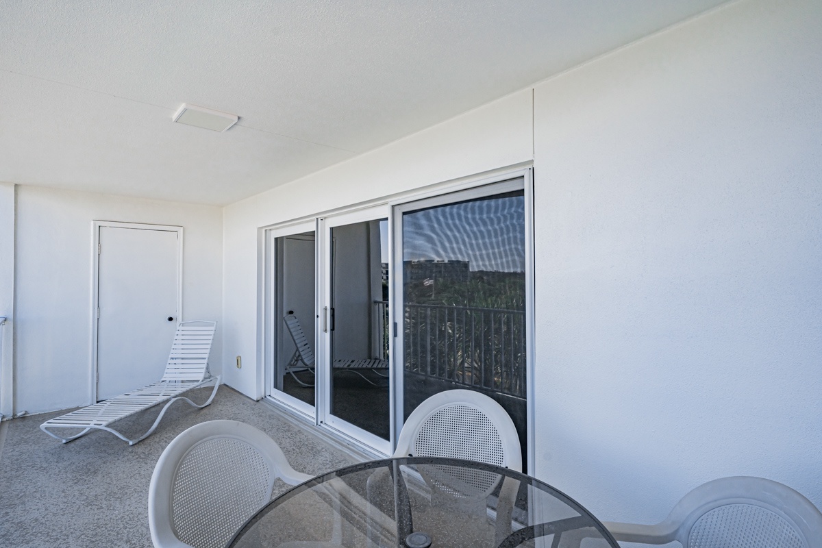 Your private balcony features modern furnishings and glass doors that showcase panoramic tropical views perfect for morning coffee or evening relaxation.