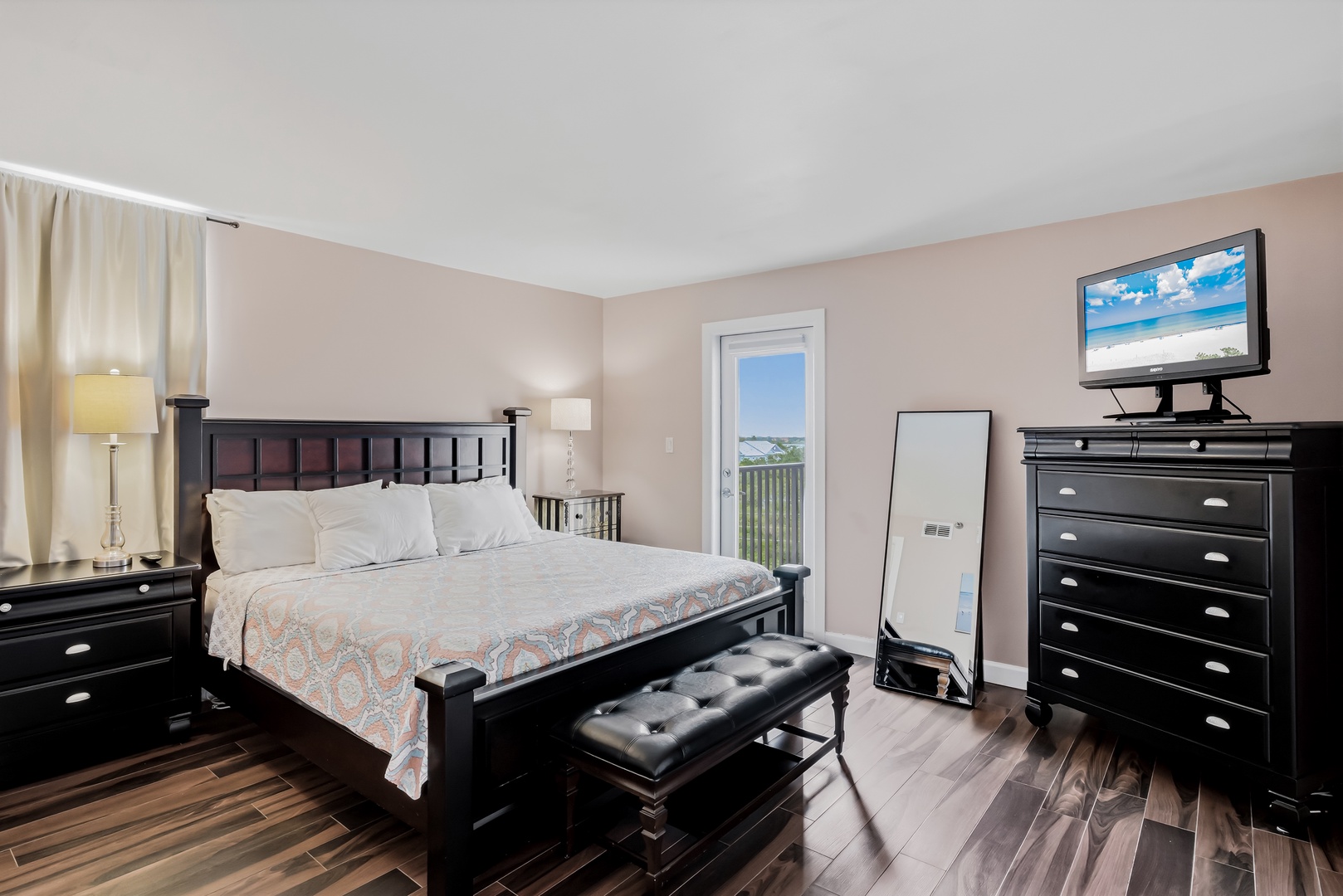 Your spacious bedroom features a plush king bed, stylish black furniture, and a private balcony with scenic views. Unwind with the flatscreen TV or relax under soft lamplight after a day of coastal adventures.