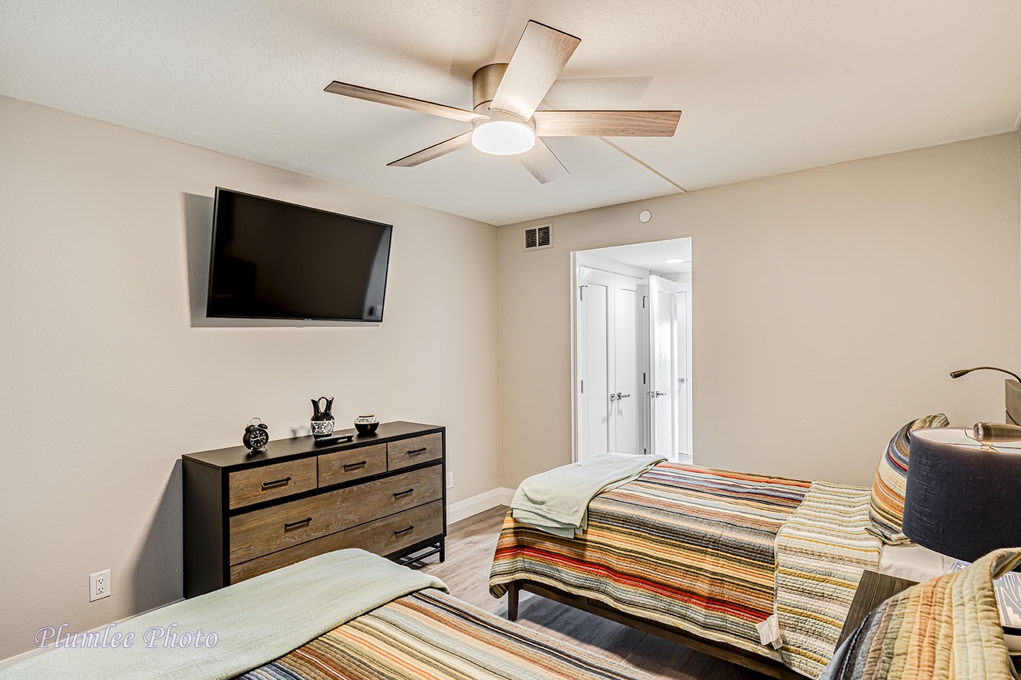 3rd bedroom has a mounted TV and ceiling fan.
