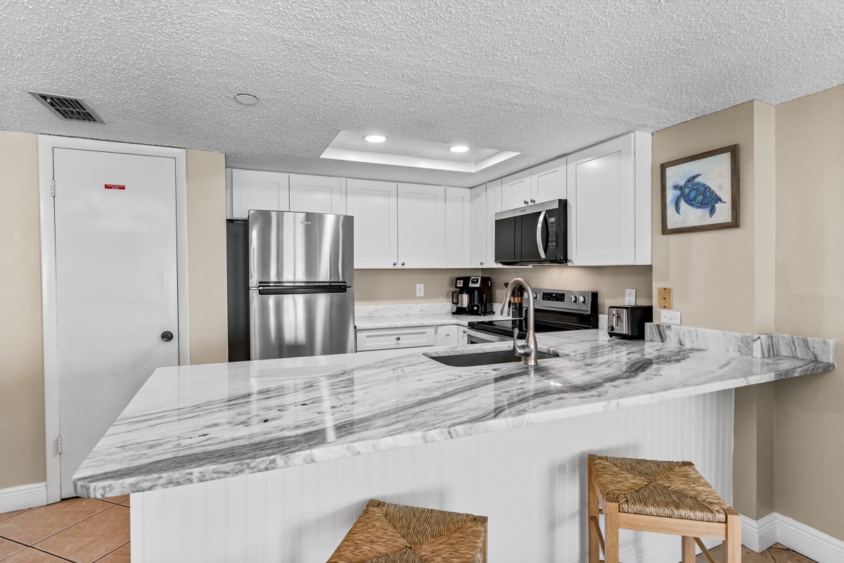 Your fully equipped kitchen features sleek marble countertops, stainless steel appliances, and a breakfast bar where you can enjoy morning coffee.