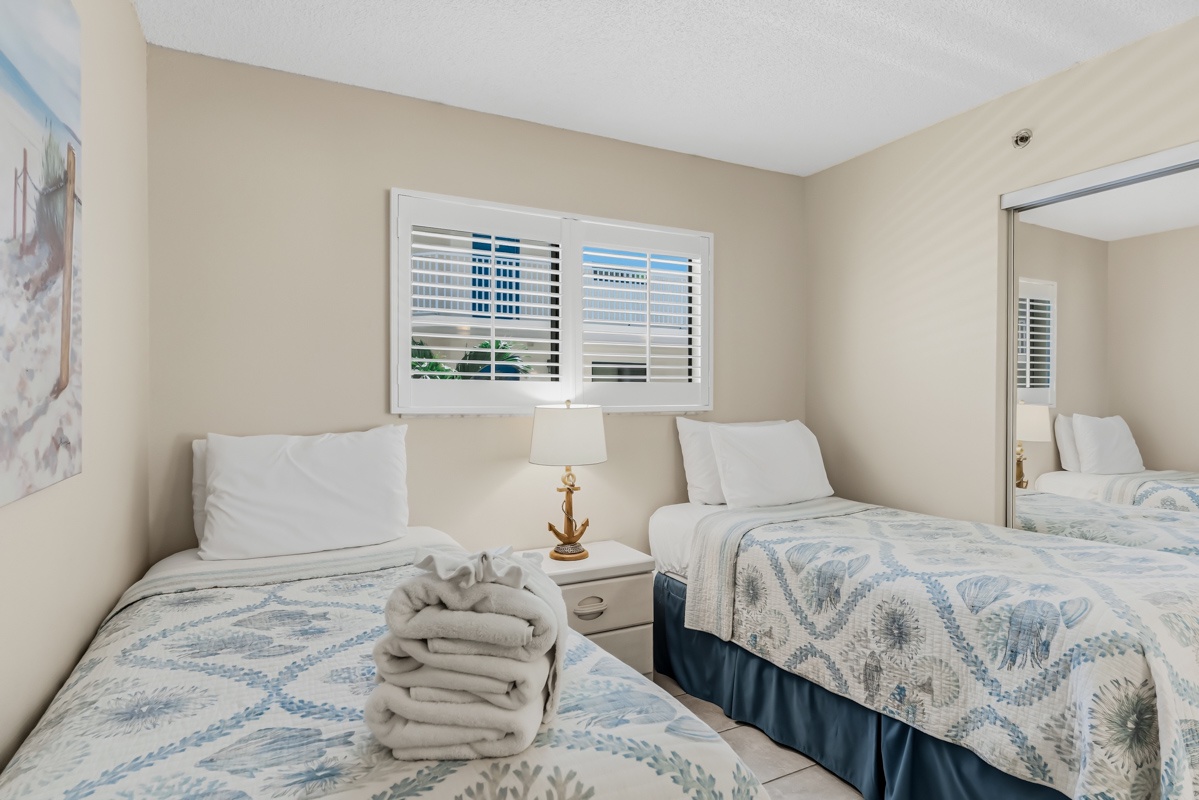 Cozy bedroom with twin beds dressed in soft coastal linens—your restful retreat after a day of sunshine and adventure.