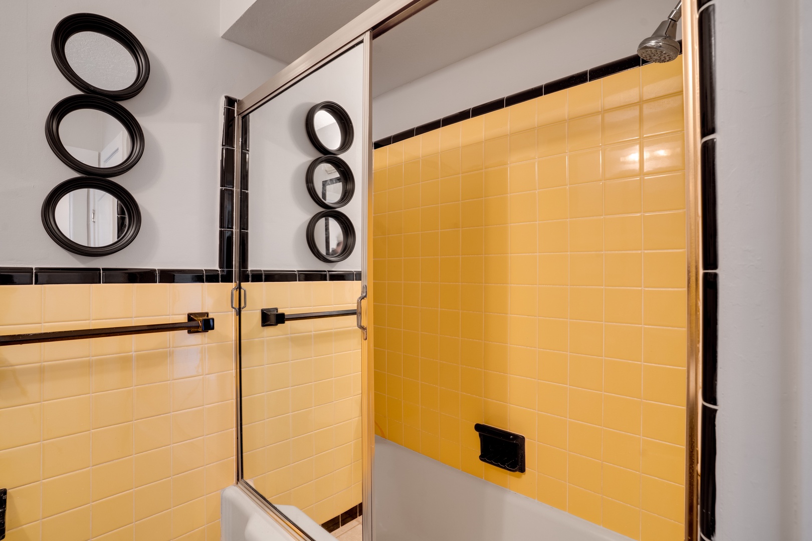 Step into your stylish bathroom featuring vibrant yellow tile work and sleek glass shower doors with modern black accents.