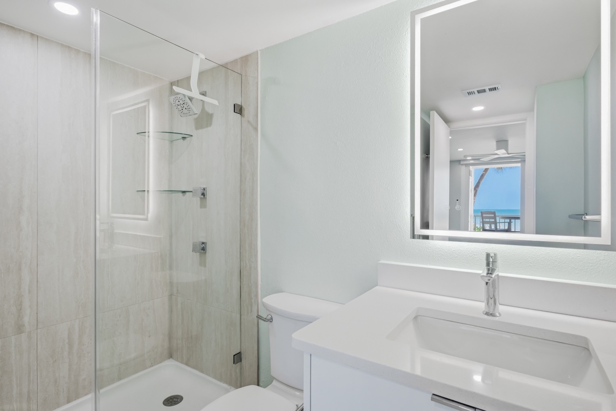 Your modern bathroom features a spacious glass shower, sleek vanity, and bright lighting—perfect for refreshing after beachside adventures.