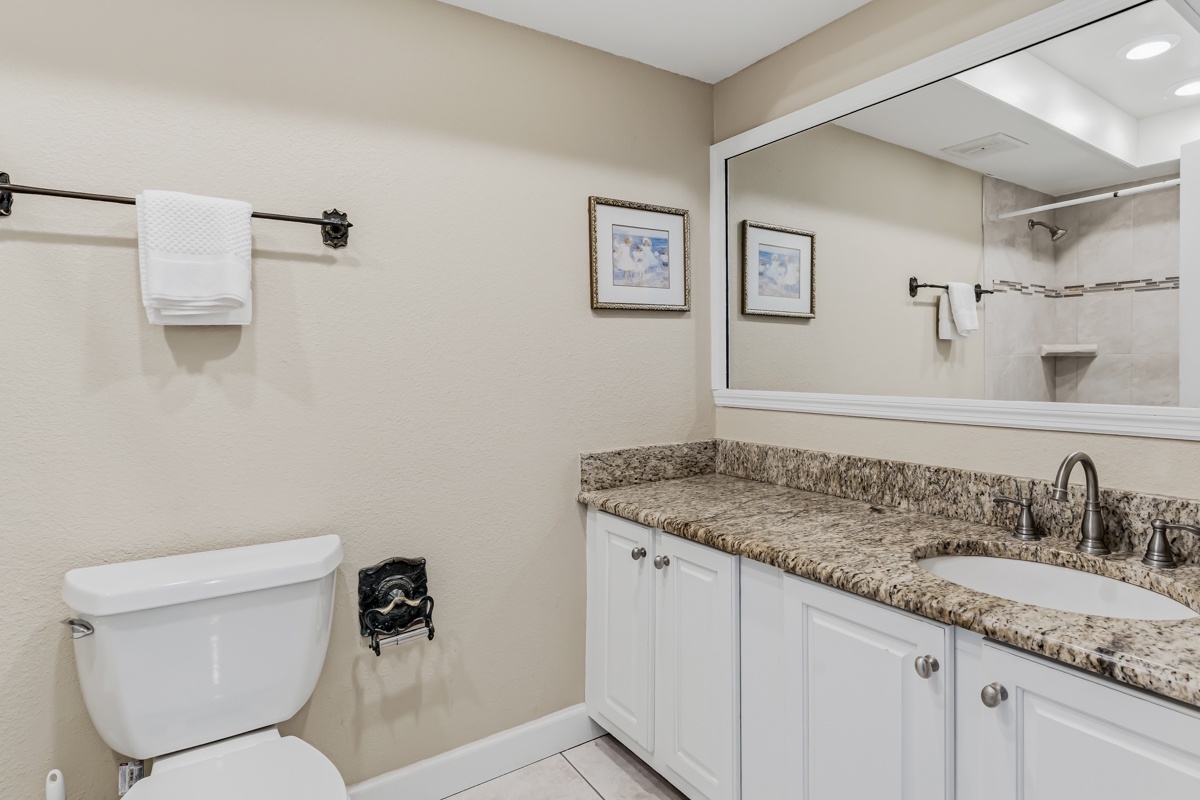 Step into your private bathroom, where a granite vanity, crisp white cabinetry, and fresh towels create a spa-like retreat just for you.