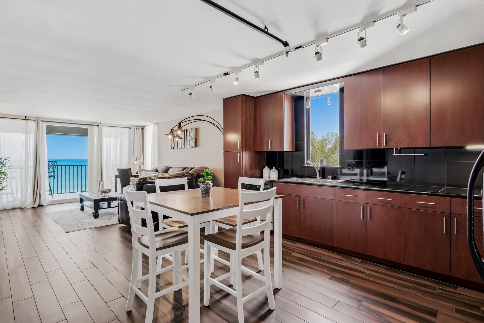 Imagine preparing meals in your sleek kitchen while the turquoise ocean stretches beyond your windows. Modern cabinetry, open living space, and a dining area flow seamlessly toward your private balcony overlooking the sea.