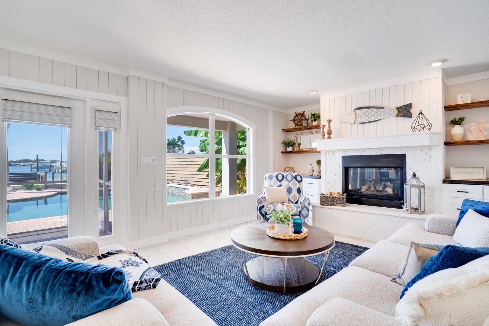 Your bright coastal living room features a cozy fireplace and stunning pool views, perfect for relaxing after sunny beach days.