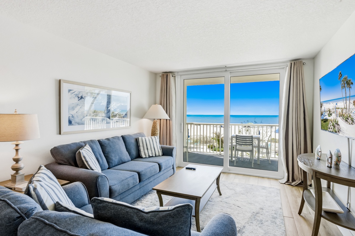 Unwind in this bright living room where ocean views stretch endlessly beyond your private balcony, perfect for morning coffee.