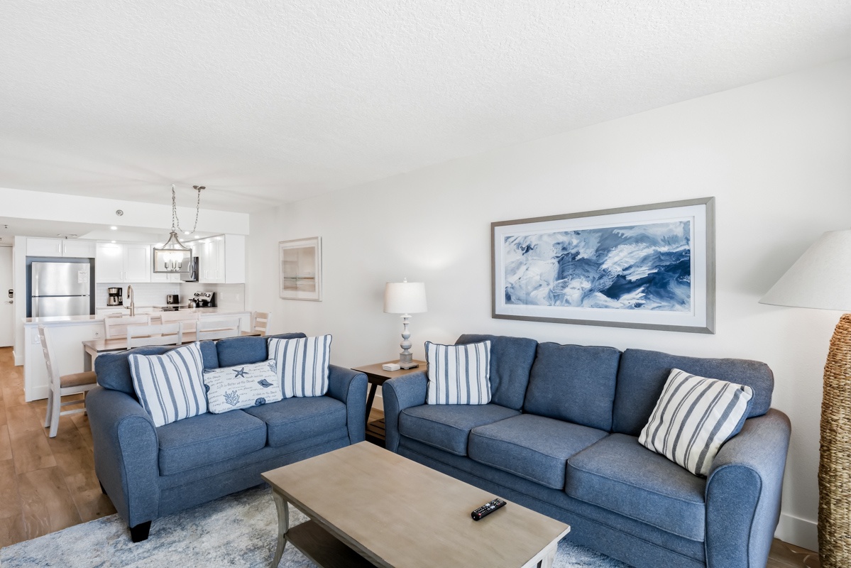 Unwind in your coastal-inspired living room with plush navy sofas and open kitchen perfect for gathering.