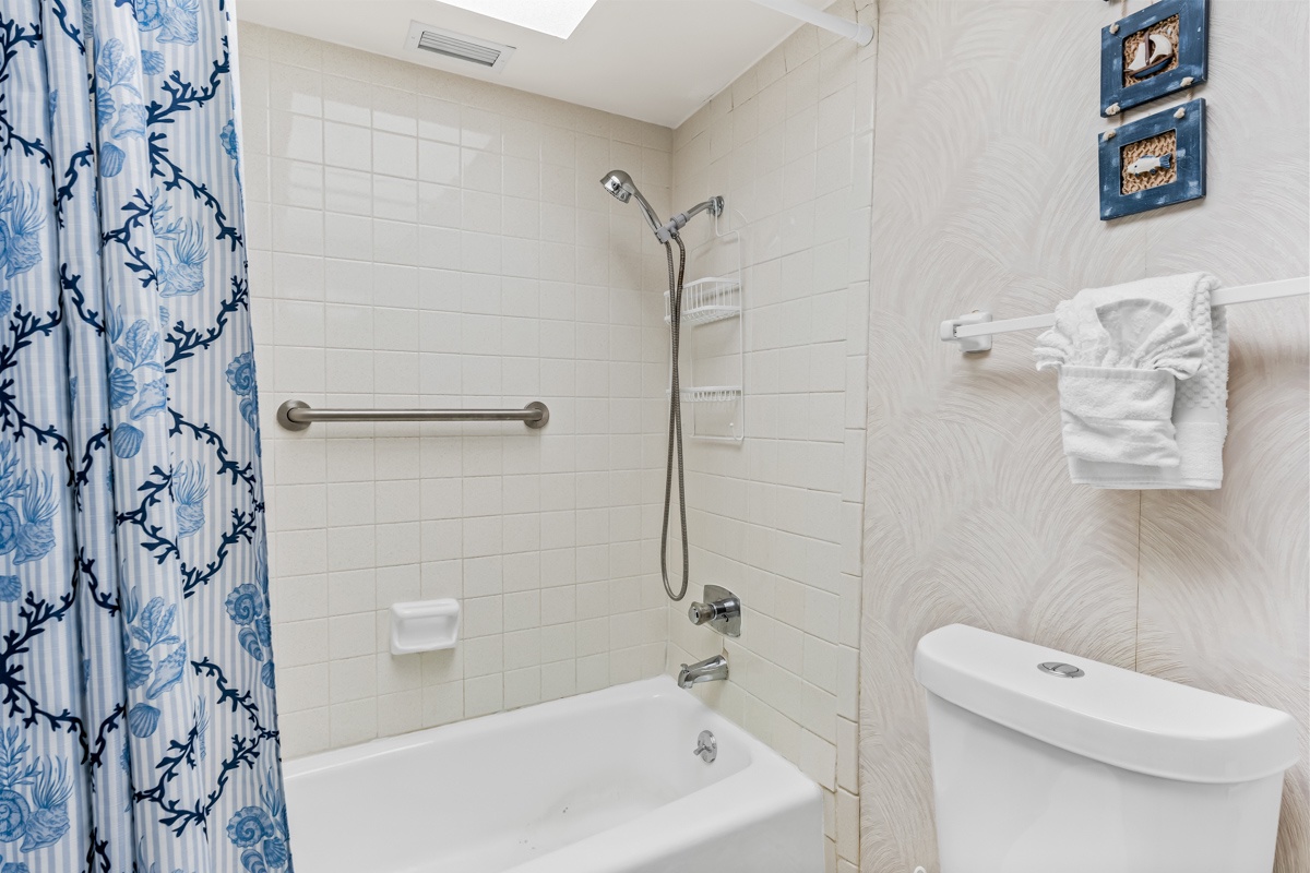 Your bathroom offers clean comfort with a relaxing tub, fresh towels, and coastal-themed touches.