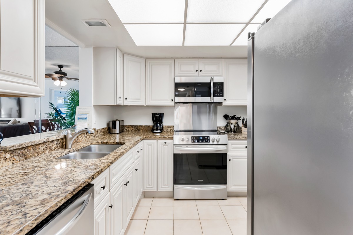 Step into your fully equipped kitchen, where gleaming granite counters and bright white cabinetry create the perfect space for preparing meals during your stay.