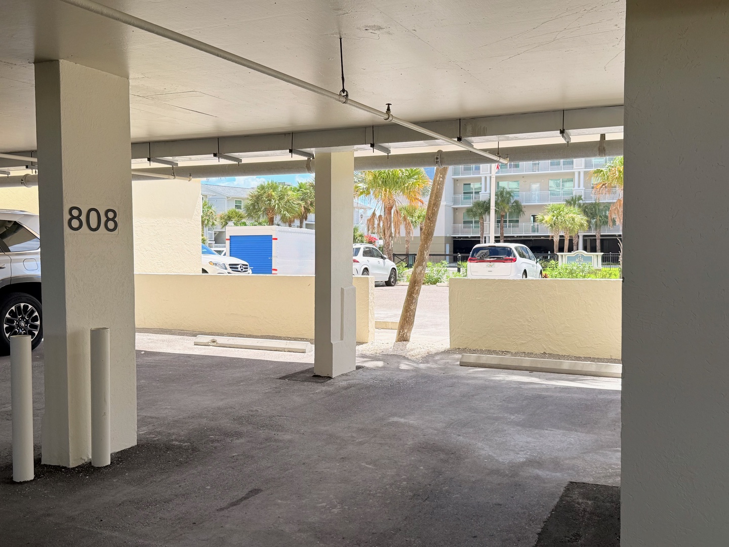 Covered parking space 808 provides convenient shelter from the elements, with nearby palm trees and surrounding buildings creating a relaxed coastal setting.