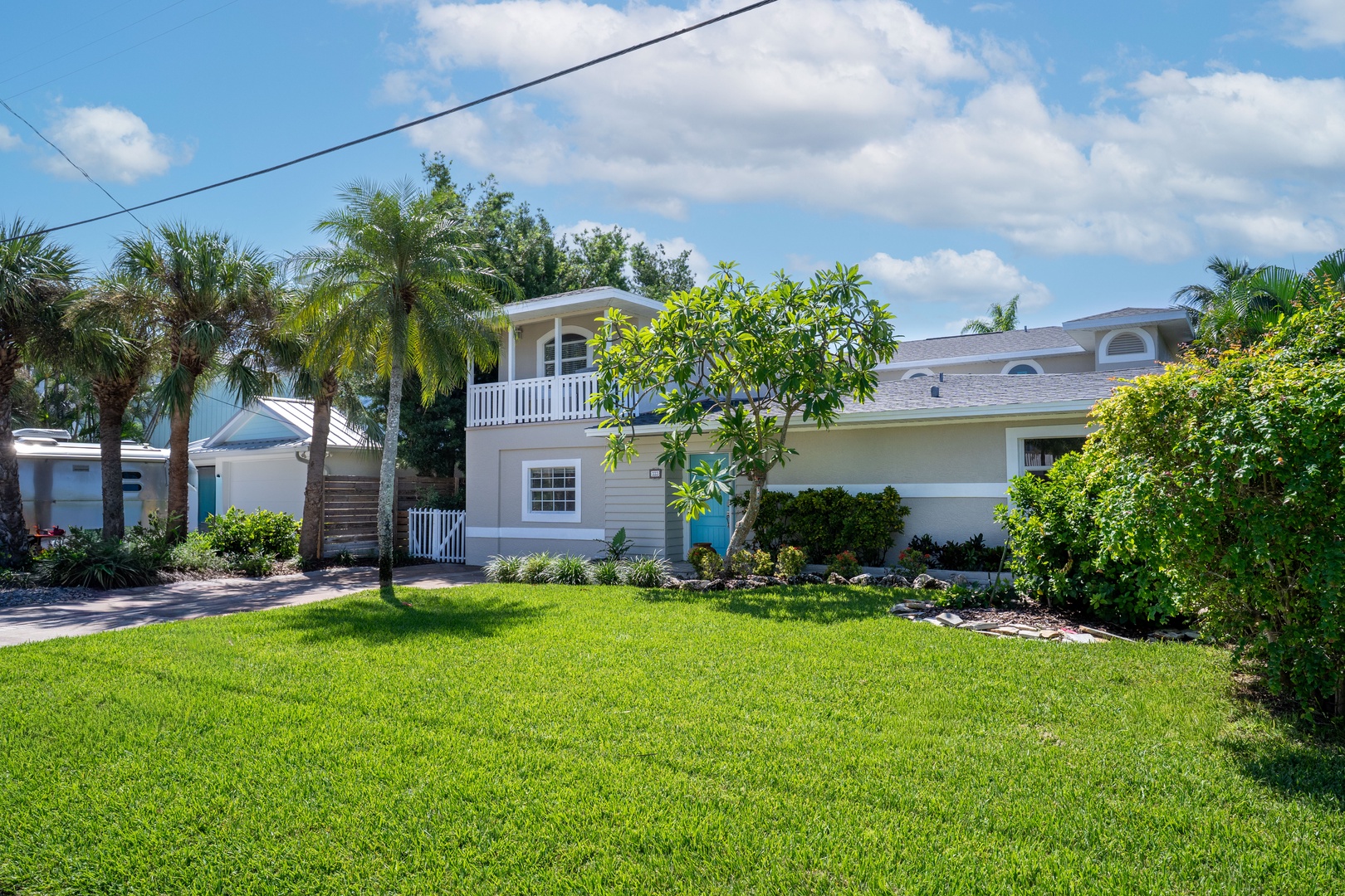 Charming coastal home with tropical landscaping and palm trees in a peaceful residential neighborhood setting.