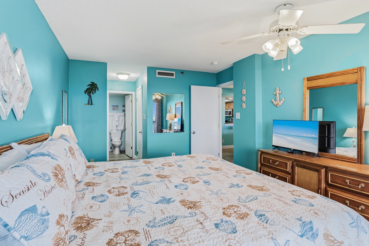 Sink into comfort in your coastal-inspired bedroom with vibrant turquoise walls, nautical decor, a ceiling fan overhead, and entertainment at your fingertips—complete with an ensuite bathroom for ultimate convenience.