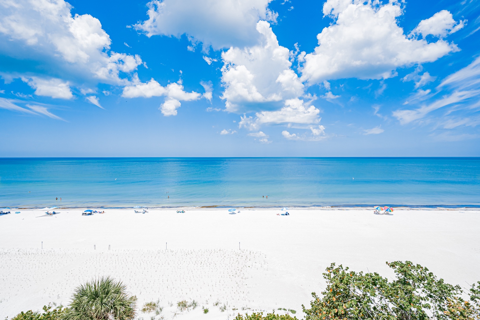 Pristine white sand beach with turquoise waters stretches endlessly along the Gulf, offering a peaceful coastal retreat surrounded by natural beauty and clear blue skies.