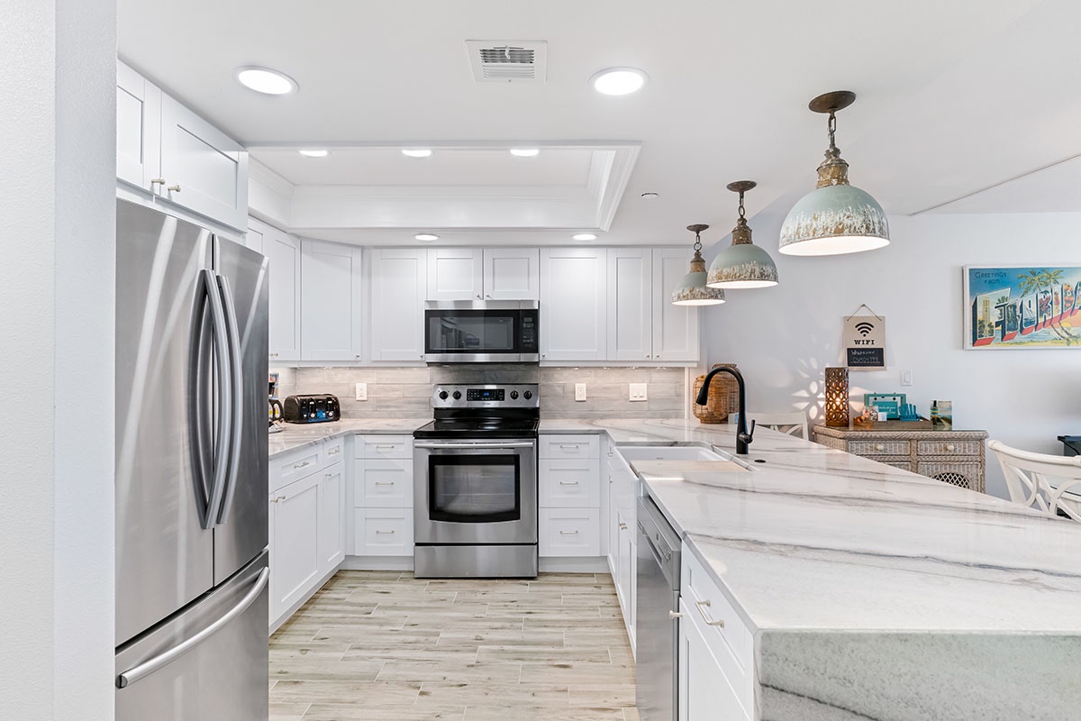 Your bright, spacious kitchen sparkles with pristine white cabinetry, marble countertops, and stainless steel appliances, creating the perfect space for memorable meals.