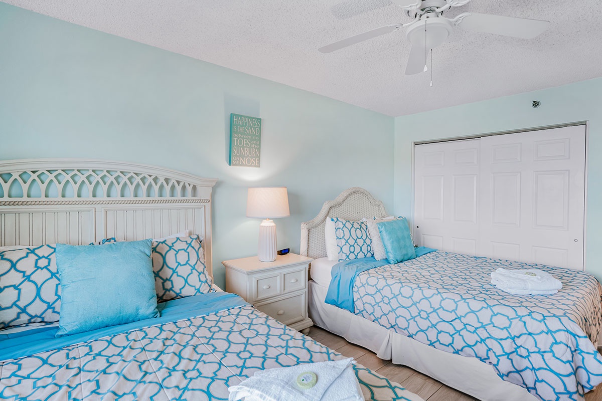 Drift off peacefully in your coastal-themed twin bedroom with soft blue linens and tropical ceiling fan for ultimate comfort.