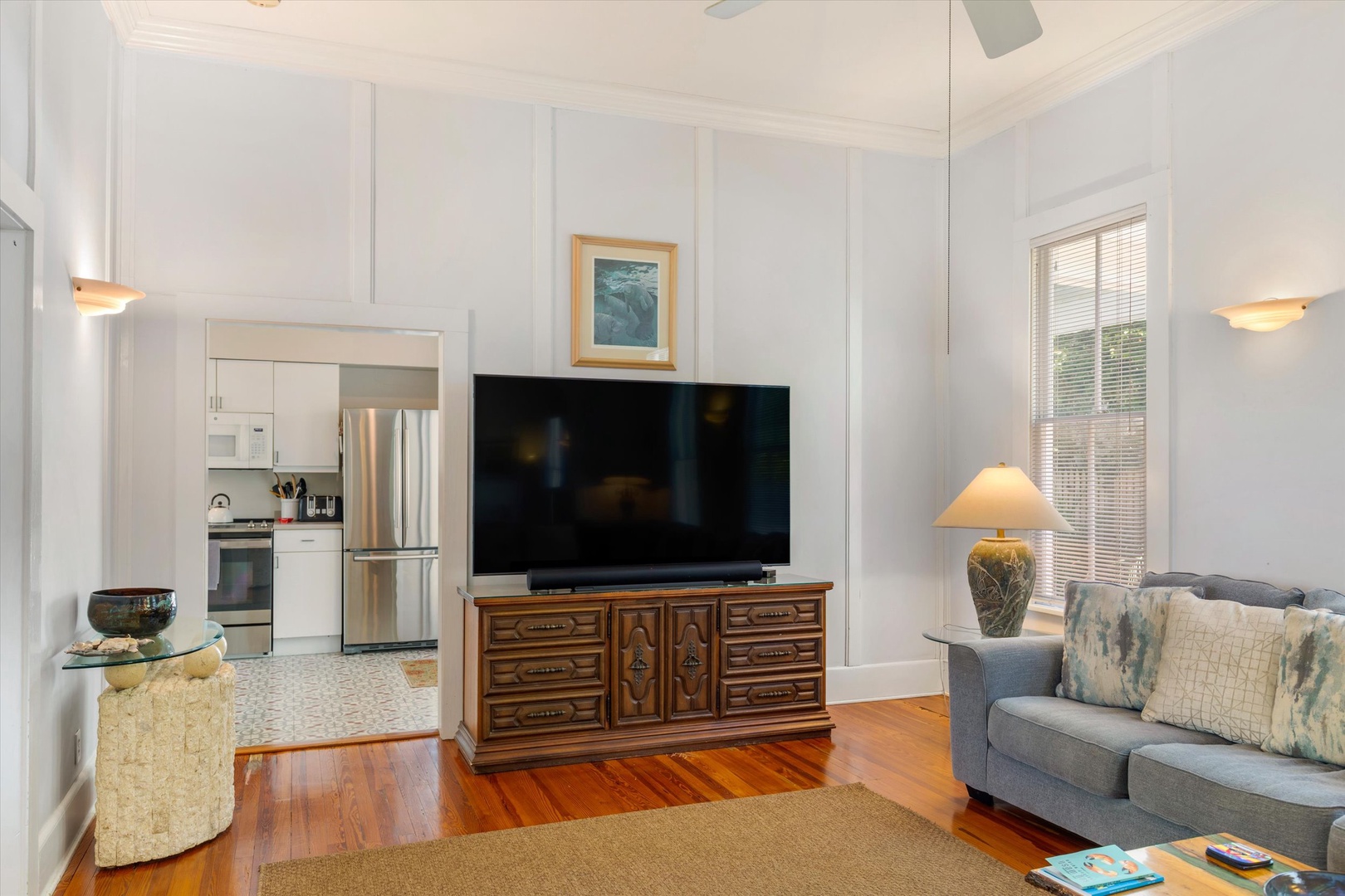 Relax in your bright and airy living room, where soft natural light pours in. Enjoy cozy evenings on the plush sofa with a large TV for entertainment and an open view into the kitchen.